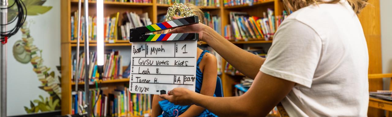 A student holding a slate on set